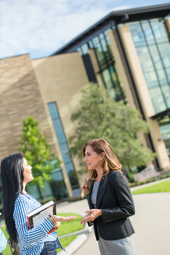 Two women talking outside of campus building